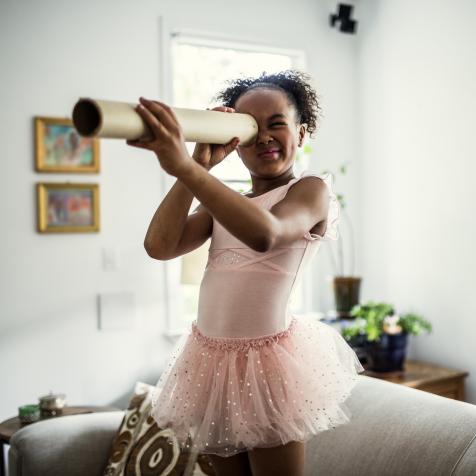 Young girl looking through homemade telescope at home