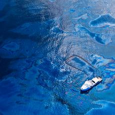 A boat wades through the oily waters of the Gulf of Mexico. The water has an iridescent rainbow sheen from the dangerous dispersant used to break up the crude oil spill.