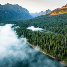 A drone photo created while flying over Hyalite Reservoir in the Gallatin Mountains of Montana. The sun is just beginning to rise and fog covers much of the lake
